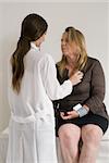 Young female doctor listening to the breathing of an older female patient.