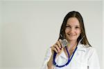 Young female doctor holding up her stethoscope and smiling. Isolated.