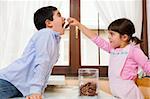 little girl giving a cookie to her brother in the kitchen