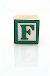 letter f on a wood block over a reflective surface