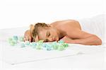 Attractive young female relaxing in spa surrounded by aromatherapy items