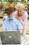 Happy senior couple using their laptop computer outdoors.  Focus on husband.