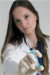 Young female doctor holding syringe in her outstretched arm. Isolated.