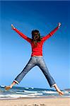 Young woman jumping on the beach and having fun