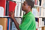 Male student selecting book from library shelf