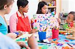 Elementary school pupil in art class showing picture to classmates