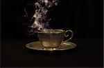Hot coffee in gold antique cup, and smoke above