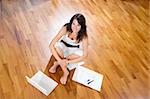 Young woman sitting in new home with laptop an blueprints, high angle view