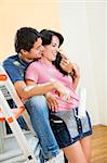 Young Hispanic couple playing with paint in new home