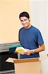 young man holding cardboard boxes and smiling