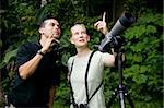 Pretty Woman with Binoculars and Man with Telescope in Rain Forest Jungle
