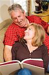 Beautiful mature couple reading together on the couch.
