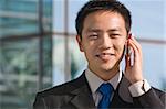 Good looking asian business man standing with formal suit and mobile phone.