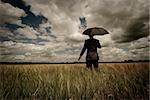 Business concept with a man holding an umbrella as a storm approaches.