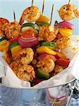 Shrimp kebabs with colorful bell peppers, red onions, and cherry tomatoes, served in a metal bucket.