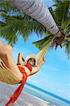 view of nice woman lounging in hammock in tropical environment