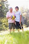 Grandfather and grandson at a park holding a ball and smiling