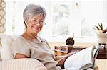 Woman in living room reading book smiling