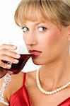 close up of a beautiful girl with necklace drinking red wine and looking in camera