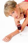 blond girl with necklace laying down on the floor near a glass of red wine