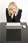 A beautiful young female executive expressing sadness at her laptop computer