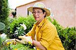 Portrait of senior Italian woman planting flowers in garden, looking at camera