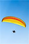 Man with a yellow paraglider flying in the sky