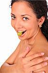 A smiling lady eats grape, standing on white background.