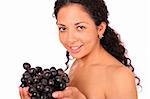 A smiling woman holds a bunch of grape in her hands, standing on white background.