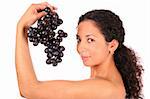 A smiling woman holds a bunch of dark grape in her hand, standing on white background.