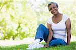 Senior female relaxing in park sitting on grass