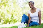 Senior woman relaxing in park sitting on grass