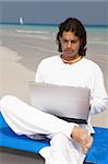 Young handsome Man on the beach using laptop