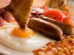 Dipping Toast into a Fried Egg on a Full English Breakfast