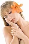 blond girl keeping her face on her hand and having a orange flower between hair