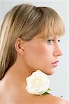 fresh portrait of a young pretty woman with a rose on her shoulder