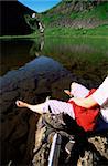 Young woman relaxing on rocks next to lake