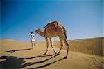 Woman leading camel across desert