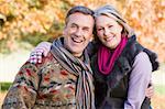 Affectionate senior couple on autumn walk with trees in background