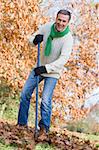 Senior man tidying autumn leaves in garden