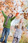 Two children throwing autumn leaves in the air