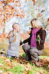 Mother and daughter throwing autumn leaves in the air