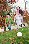 Mother and children playing football in autumn garden