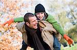 Father giving son piggyback through autumn woods