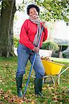 Mature woman collecting autumn leaves in garden