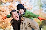 Father giving son piggyback in autumn woodland