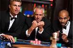 Group of male friends gambling at roulette table in casino