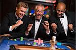 Group of men celebrating win at roulette table in casino