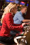 Woman sitting at slot machine in casino parlour