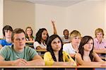 College student with hand raised in university lecture hall